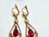 a pair of gold earrings with red stones on them