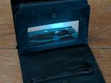 someone is holding a black wallet on a wooden table