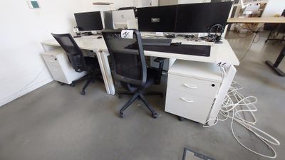deux ordinateurs posés sur les bureaux de la salle