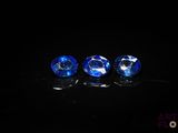 trois saphirs bleus posés sur une surface noire