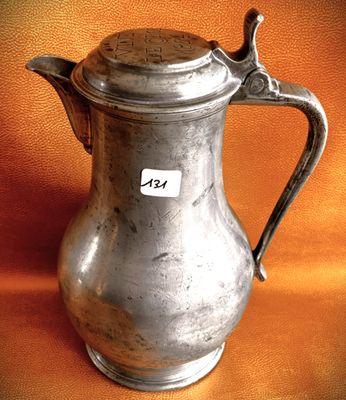 a silver pitcher with a tag on it sitting on a table