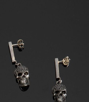 une paire de boucles d'oreilles en forme de crâne en argent, avec une tige au milieu
