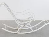 a white rocking chair in a room with a white wall