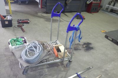 un chariot rempli d'outils posé à même le sol dans un garage
