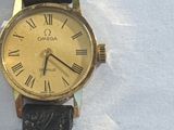 a gold watch with roman numerals on a black strap