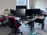 an image of a desk with three computers and a chair