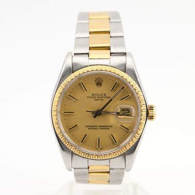 une photo d'une montre Rolex dorée et argentée posée sur une surface blanche