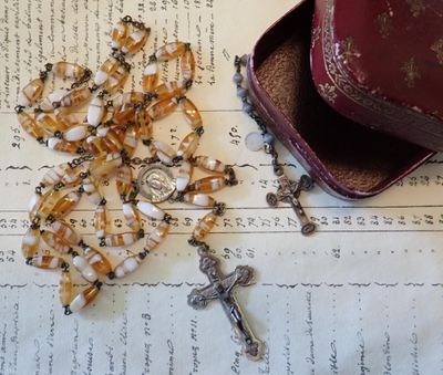 a rosary, a hat, and a book on a table