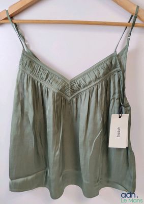 a close up of a green top hanging on a wooden hanger