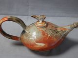 a small teapot with a bird on top of it