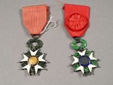 deux médailles ornées d'un ruban rouge et une médaille d'or posée sur un fond gris