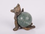 statue d'un ours tenant une boule de pierre verte sur une surface blanche