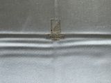 silver satin envelope with a gold logo on the front of it