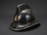 un vieux casque de pompier noir orné d'un insigne doré