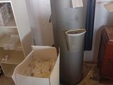 une poubelle et un chauffe-eau dans un coin de la pièce