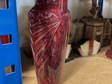 a red vase sitting on top of a shelf in a store