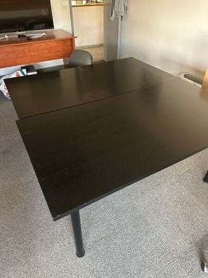 a black desk with a chair and a television in the corner