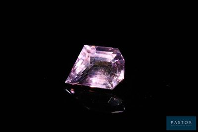 a close up of a pink diamond on a black surface