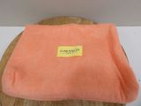 an orange blanket sitting on top of a wooden table next to a white wall
