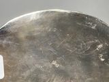 an oval silver platter with a handle on a gray surface