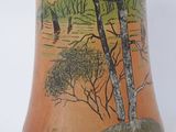 a vase with a painting on it on a white surface