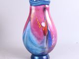 un vase en verre coloré posé sur une surface blanche
