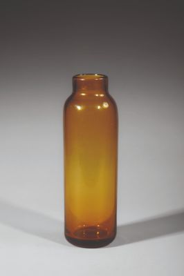 une bouteille en verre brun posée sur une surface blanche