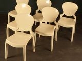 four white plastic chairs are arranged in a circle on a black floor