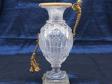a glass vase with a gold handle on a stand