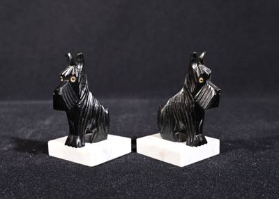 une paire de figurines de chiens noirs sur des socles en marbre, sur fond noir