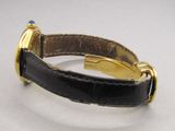 une montre en or avec un bracelet en cuir noir sur un fond blanc