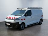 La camionnette blanche est garée dans une pièce blanche, avec une bande rouge et blanche sur le côté.