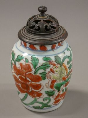 a vase with a lid that has a flower design on it