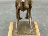 bronze statue of a dog on a marble base on a gray background