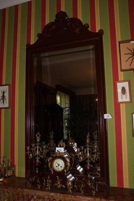un miroir et une horloge posés sur la cheminée d'une pièce
