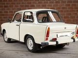 a small white car that is parked in front of a brick wall