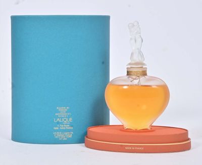 une image représentant un flacon de parfum à côté d'une boîte bleue