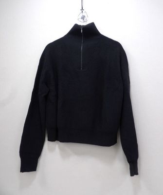 a close up of a black sweater hanging on a white wall