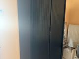 a black cabinet in the corner of a bathroom