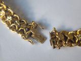 two pieces of gold bracelets on a white surface next to each other