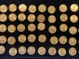 des pièces d'or sont disposées dans une vitrine posée sur un socle noir
