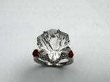 a close up of a diamond ring with a red bead