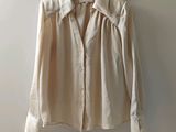 une chemise beige suspendue à un cintre devant un mur blanc