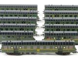 several green train cars are lined up on a white surface
