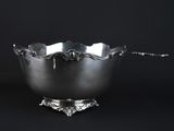 a silver bowl on a stand against a black background