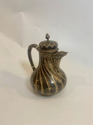 an antique silver plated coffee pot on a white background