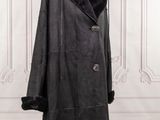 a black coat on a mannequin stand in front of a white wall