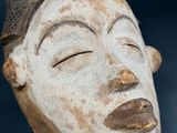 a close up of a wooden mask on a table