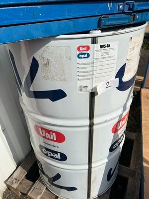 un grand fût blanc posé sur une palette, à côté d'un conteneur bleu