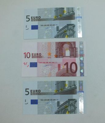 Trois billets de cinq devises différentes sont représentés sur un fond blanc.
